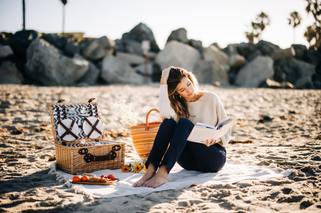 girl sitting on the beach having a picnic and reading